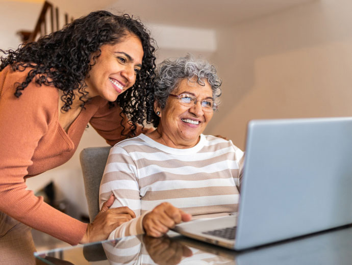adult daughter and mature mom using a laptop together 