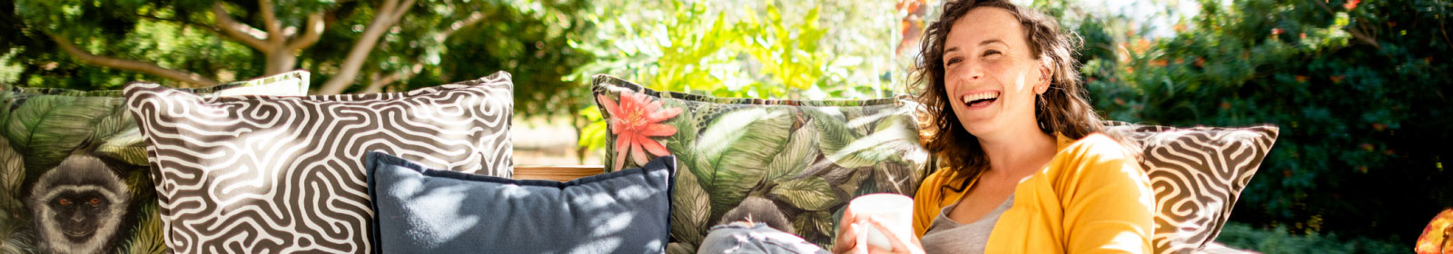 a woman sitting on an outdoor bench with colorful pillows