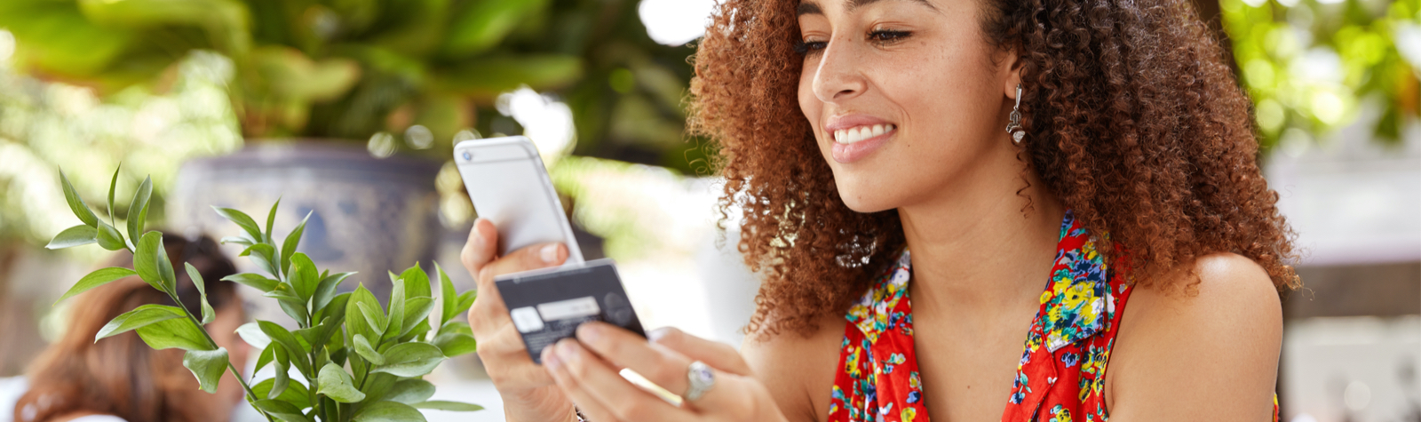 Business Checking, young woman looking at her card and phone