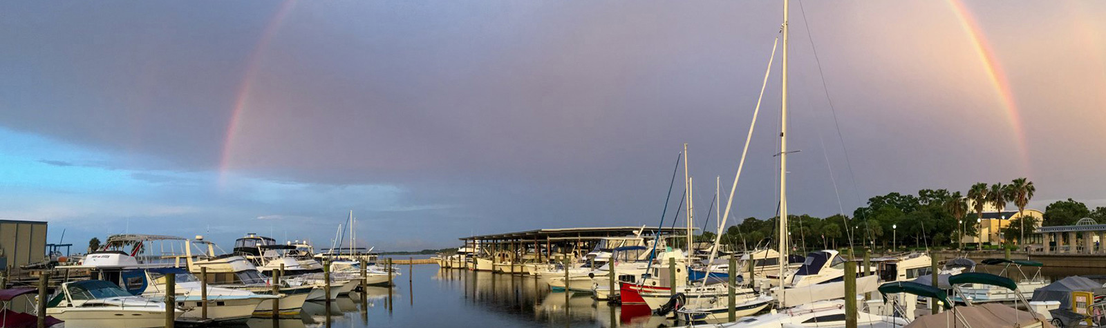 boats at dock with a rainbow in the harbor